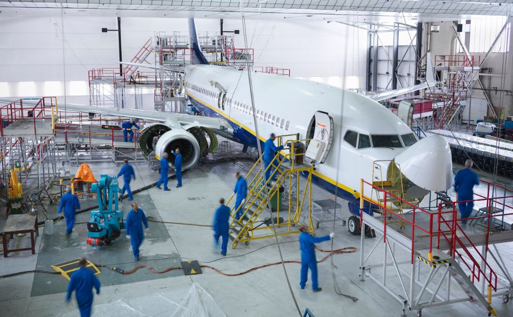 Engineers working with aircraft in repair hangar